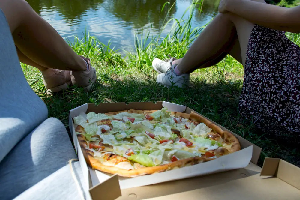 Friends eating pizza near lake