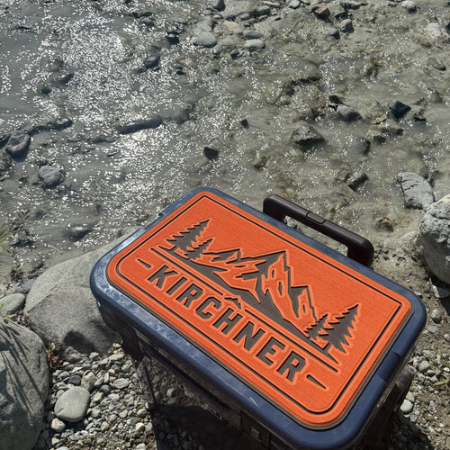 Kirchner name cooler top pad in orange and charcoal foam on a rocky riverbank